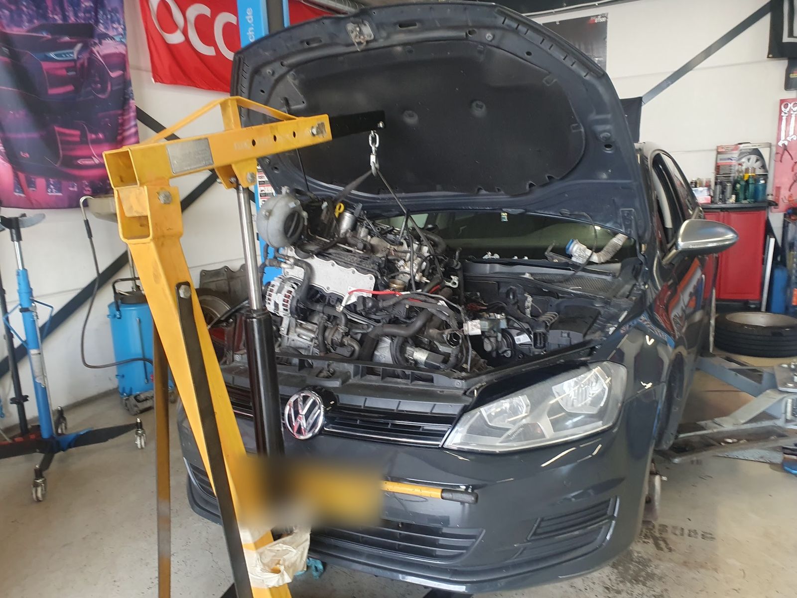 Volkswagen met een gele motorlift boven de geopende motorruimte
