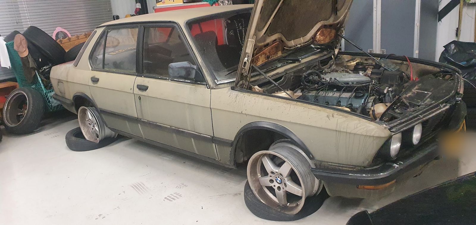 Klassieke beige BMW met geopende motorkap in de werkplaats