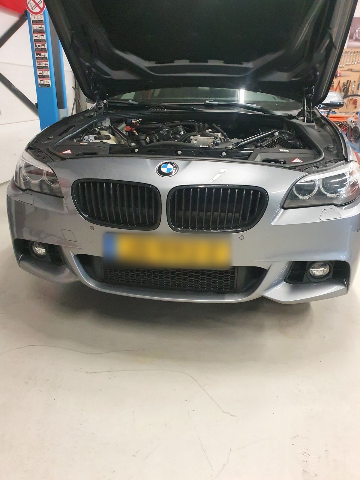 Grijze BMW met geopende motorkap in de werkplaats