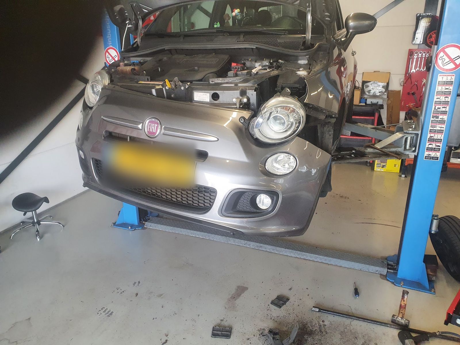 Grijze Fiat 500 op de brug met losse voorbumper en koplampen eruit